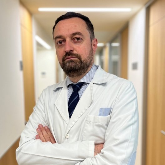 Dr. Francisco Mera, médico de familia, en bata blanca en un pasillo clínico